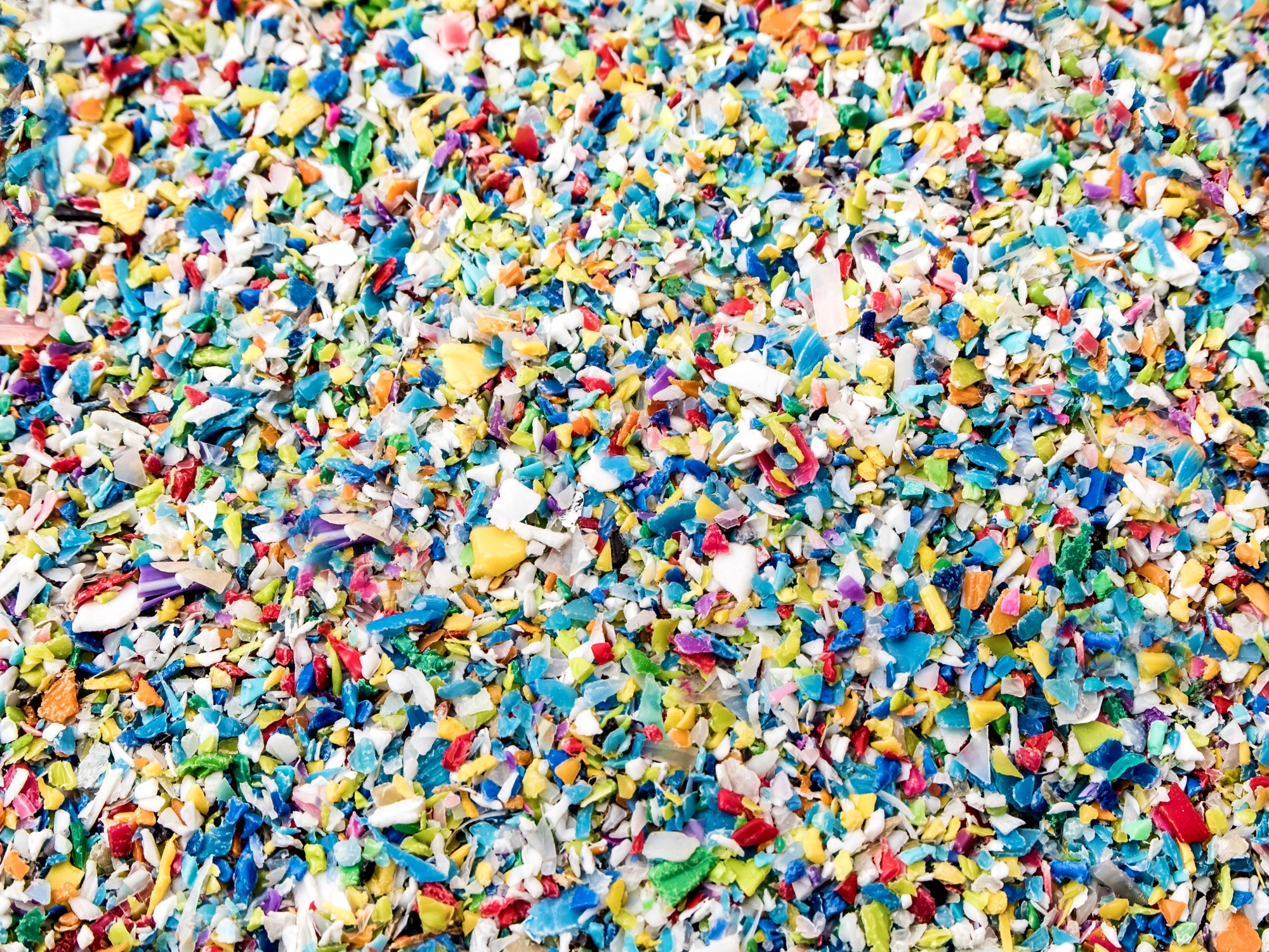 Crushed plastic in multiple colours, ready for recycling.