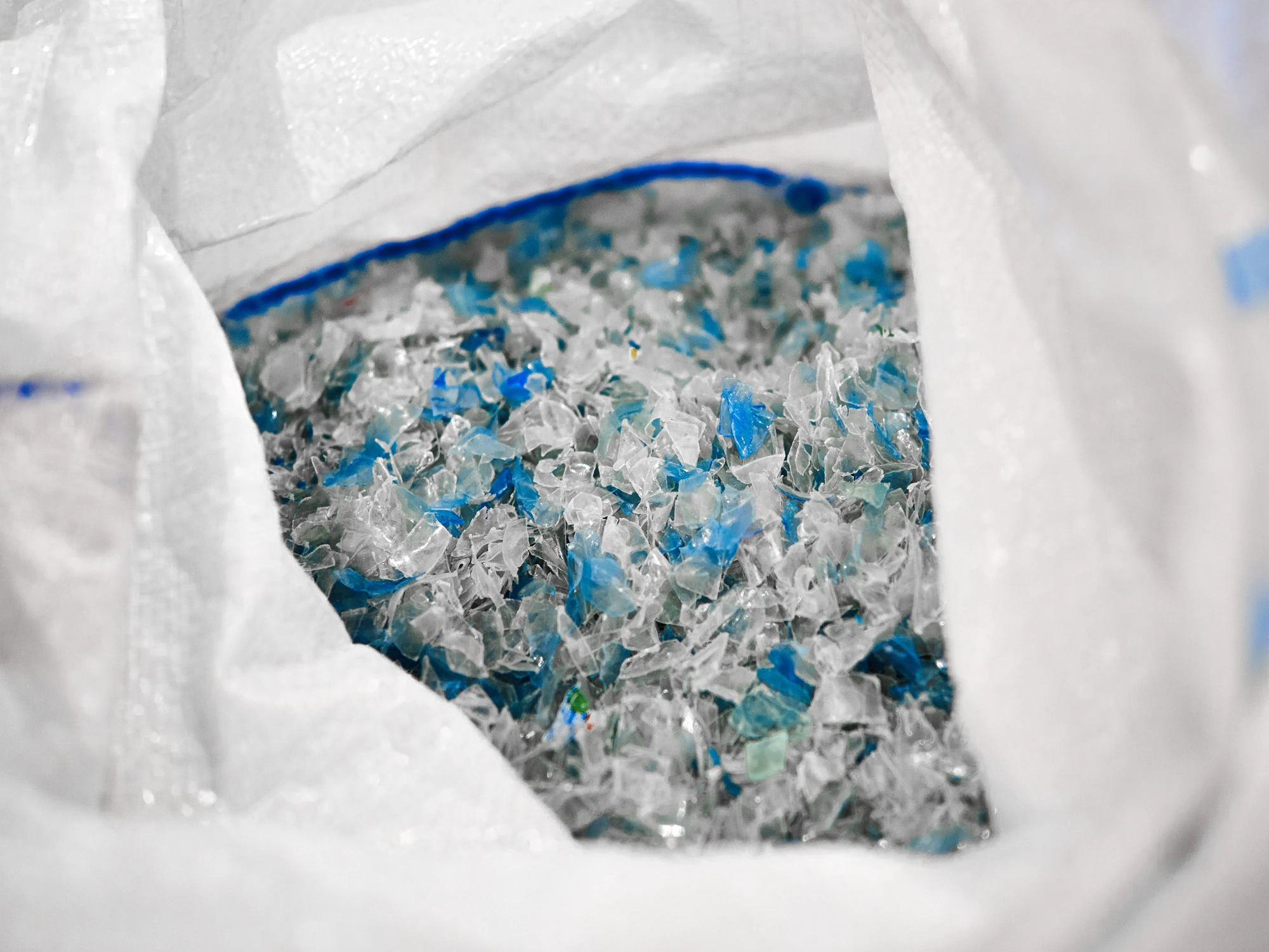 Crushed pieces of plastic bottles in a white bag.