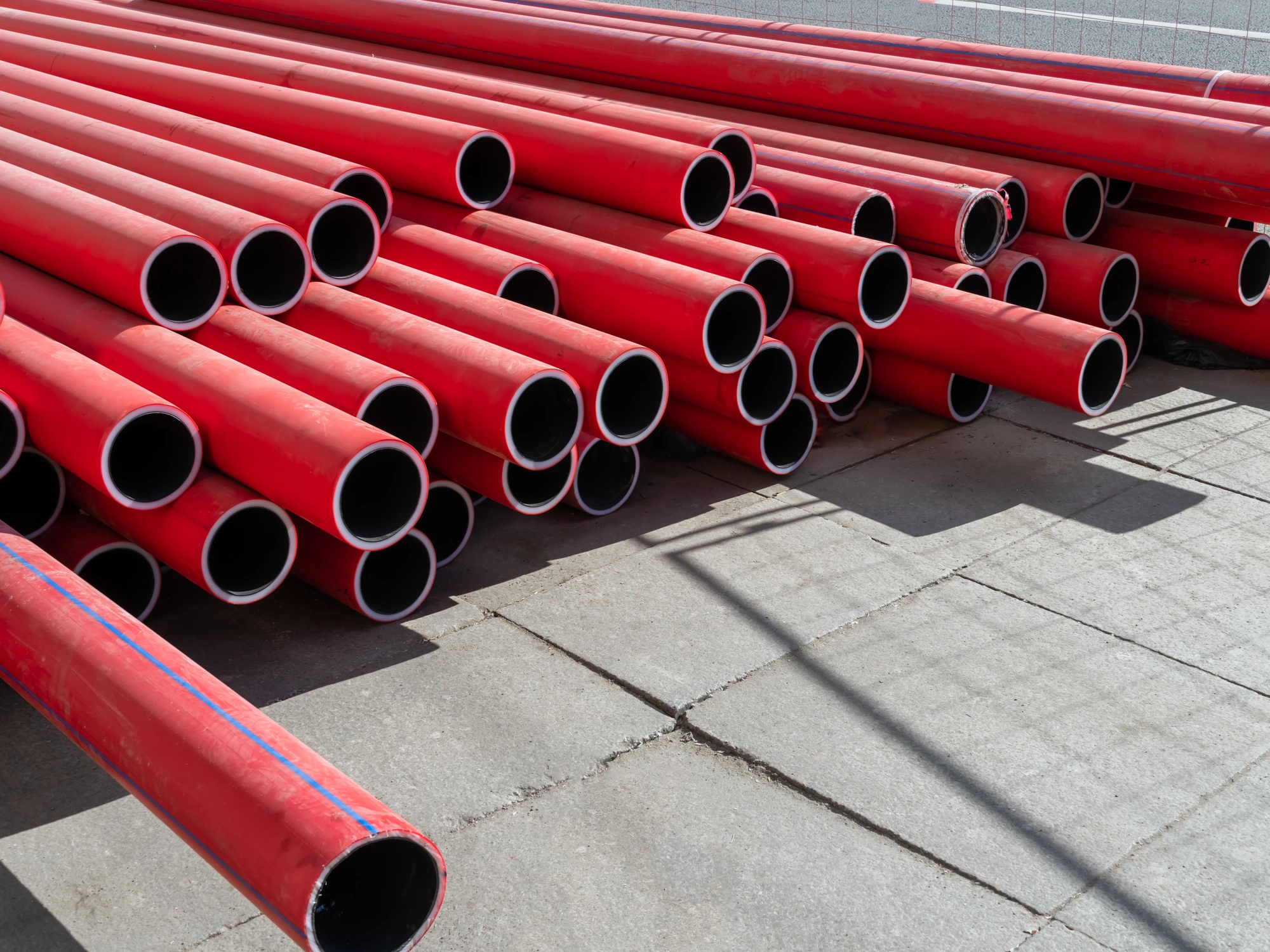 Stack of newly manufactured red HDPE pipes.