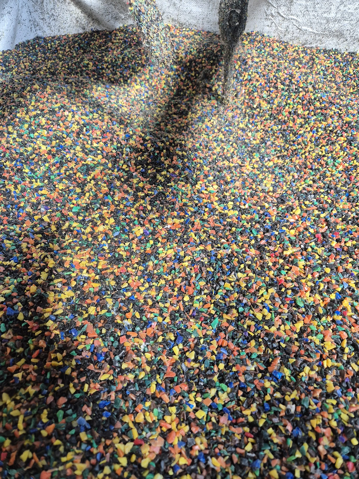 Crushed plastic in multiple colours, ready for recycling.