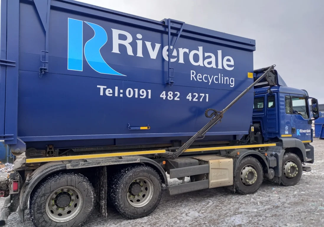A blue Riverdale Recycling truck parked on a gravel surface.