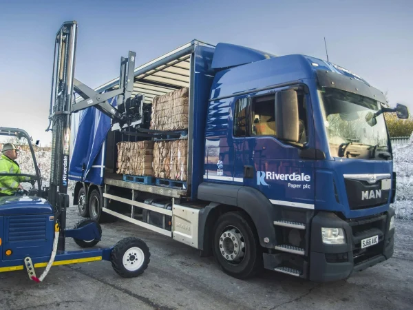 A forklift loading baled cardboard onto a Riverdale Recycling lorry.